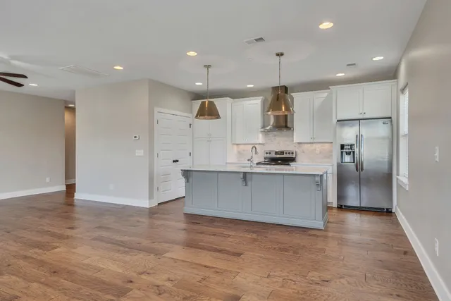 a large kitchen with a large counter top stainless steel appliances and cabinets