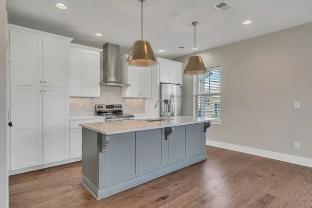 a kitchen with stainless steel appliances granite countertop a sink a stove a refrigerator and island with wooden floor