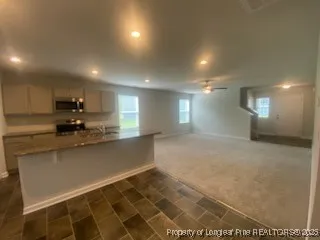 a large kitchen with stainless steel appliances granite countertop a sink a stove a microwave a counter top and cabinets