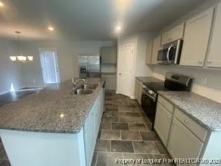 a large kitchen with kitchen island granite countertop a sink and dishwasher a stove top oven with wooden floor