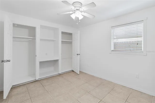 an empty room with a ceiling fan and a window