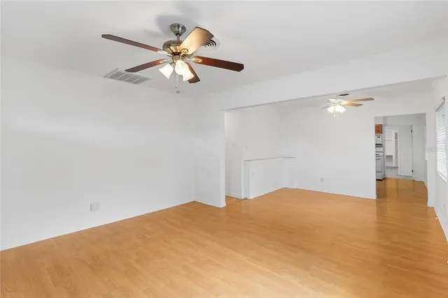 a view of empty room with wooden floor and ceiling fan