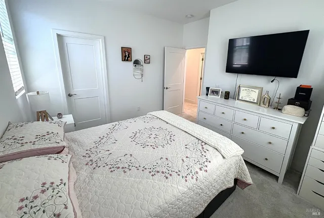 a bedroom with a bed and a flat tv screen on a dresser