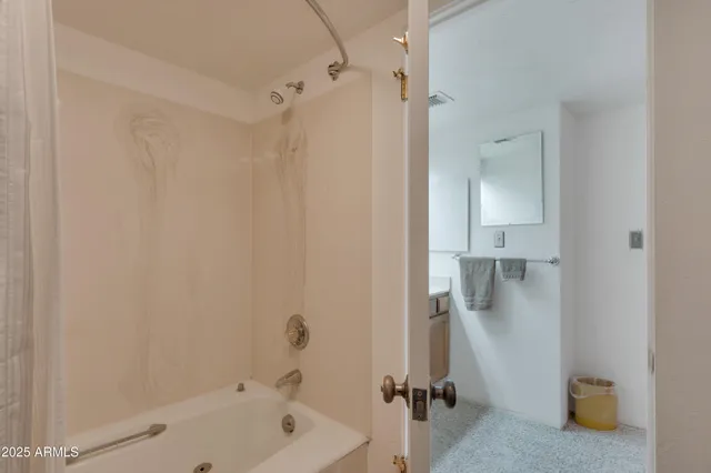 a bathroom with a tub a mirror and a shower