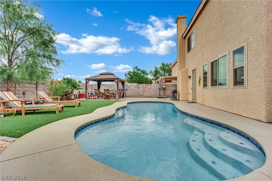 1724 Millstream Way Henderson, NV 89074 - Photo 41 of 60 A private backyard oasis features a freeform pool with steps and an adjacent shaded gazebo for relaxation.