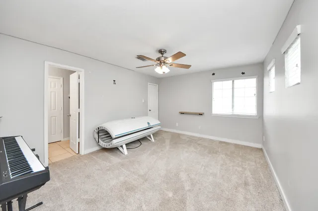 an empty room with windows and ceiling fan