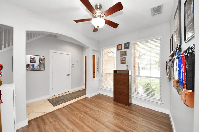 a view of empty room with wooden floor and fan