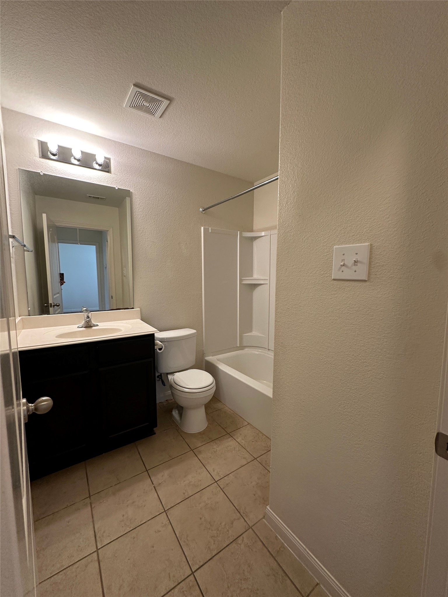 104 Millers Loop Jarrell, TX 76537 - Photo 11 of 11 The bathroom features neutral-toned tile flooring, a dark vanity with a light-colored countertop, and a shower-tub combination