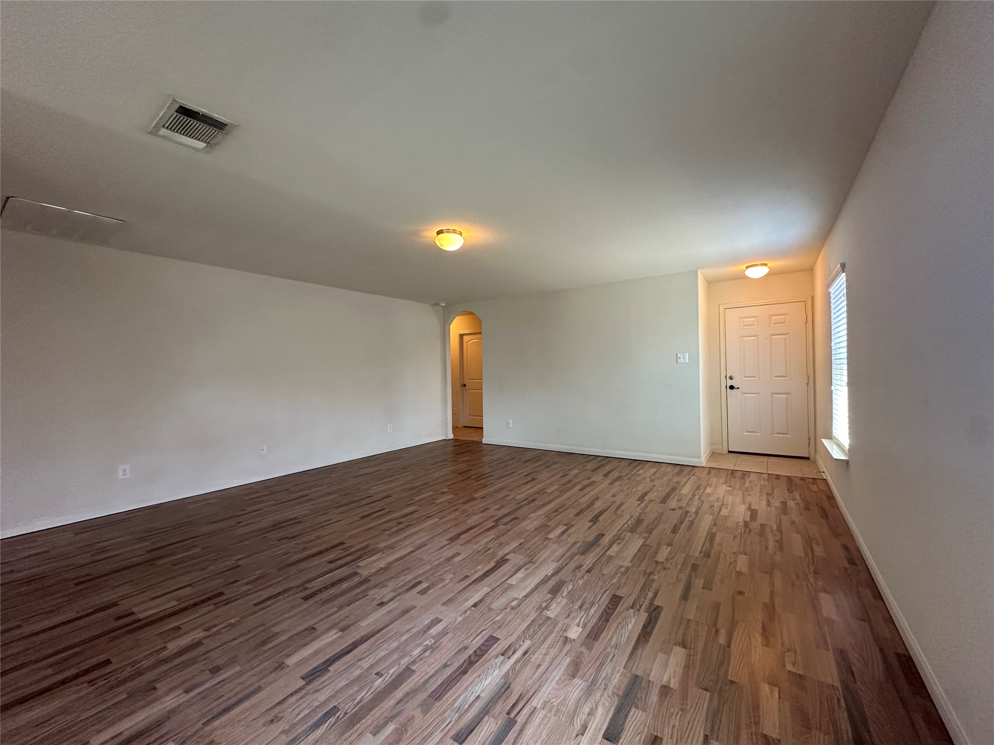 104 Millers Loop Jarrell, TX 76537 - Photo 2 of 11 This expansive room features rich hardwood flooring, light-colored walls, and a ceiling-mounted light fixture, providing a bright and welcoming atmosphere