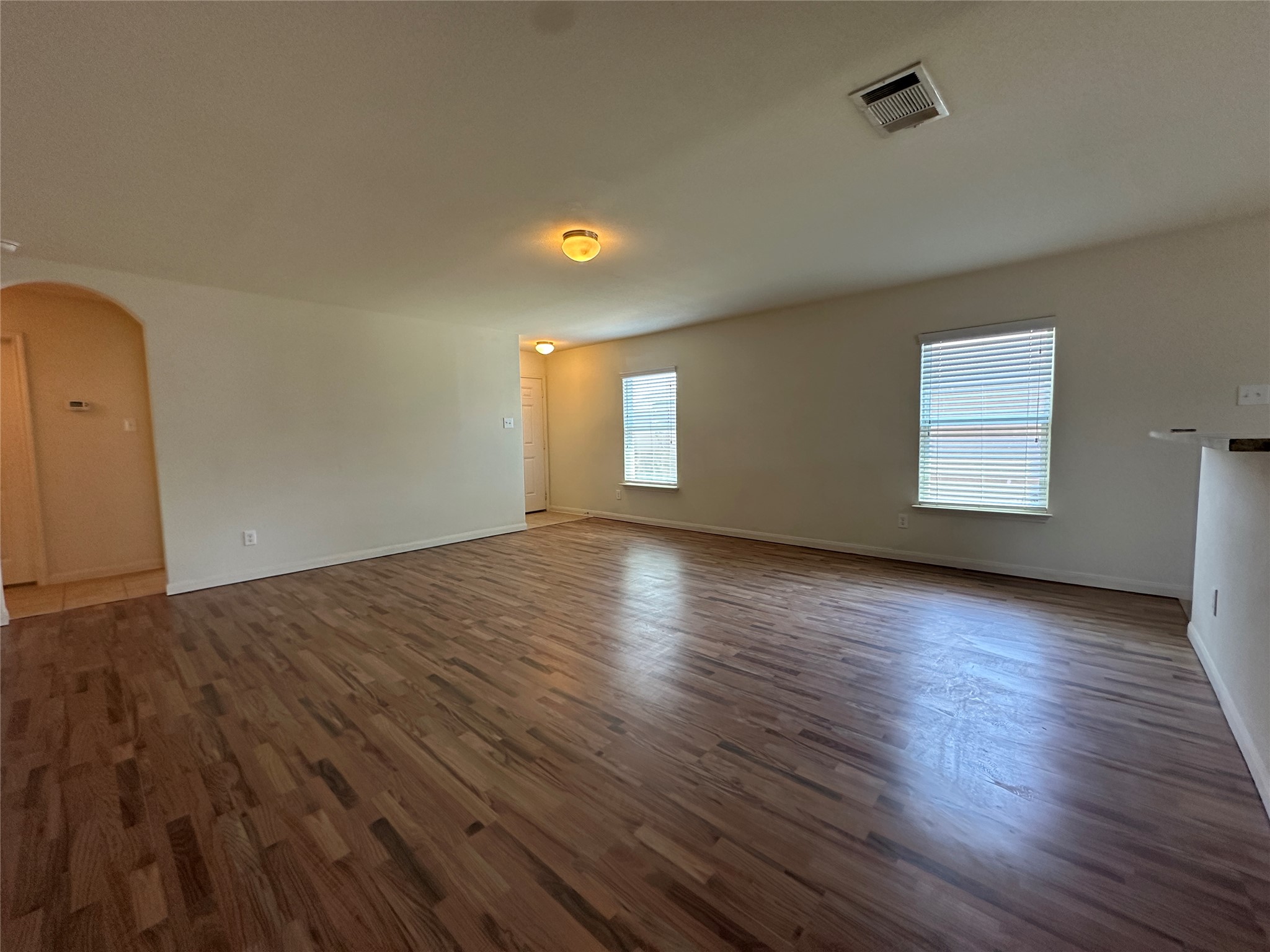 104 Millers Loop Jarrell, TX 76537 - Photo 4 of 11 Spacious room featuring wood flooring, neutral tone walls, and two windows with blinds