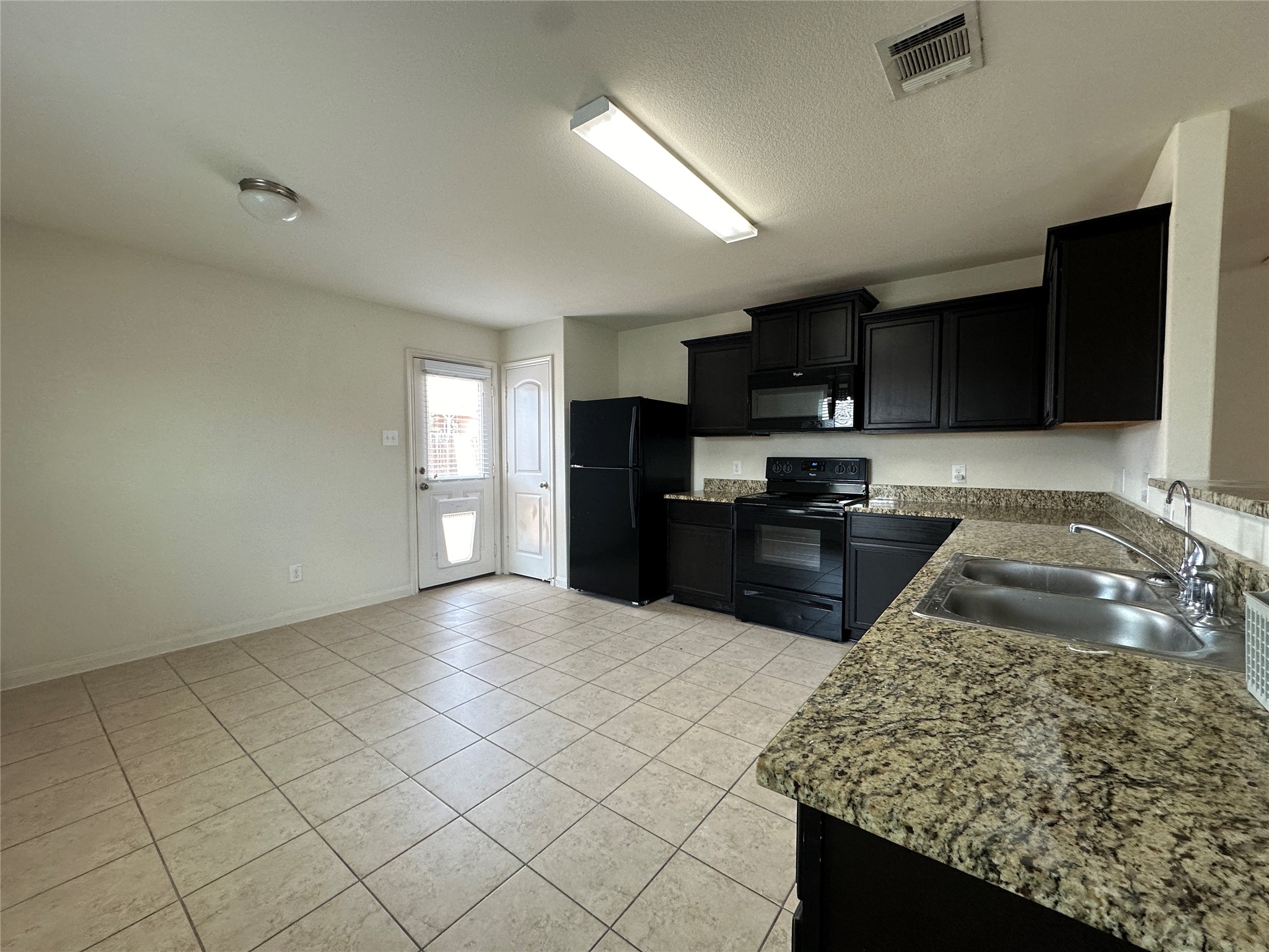 104 Millers Loop Jarrell, TX 76537 - Photo 6 of 11 The kitchen features black cabinetry, granite countertops, and black appliances