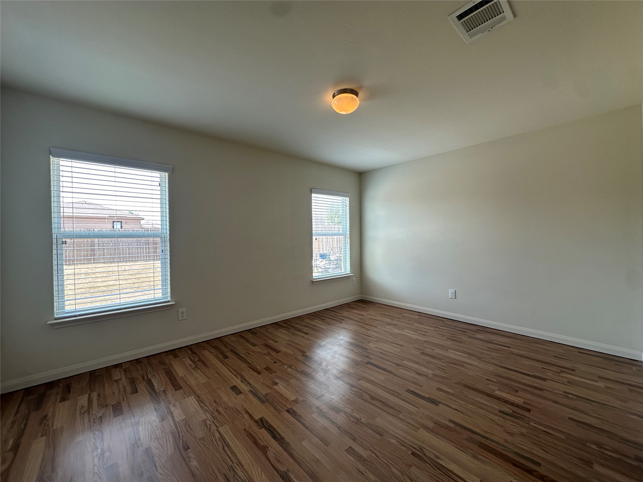 104 Millers Loop Jarrell, TX 76537 - Photo 7 of 11 This room features hardwood flooring, two windows with blinds, and a ceiling-mounted light fixture