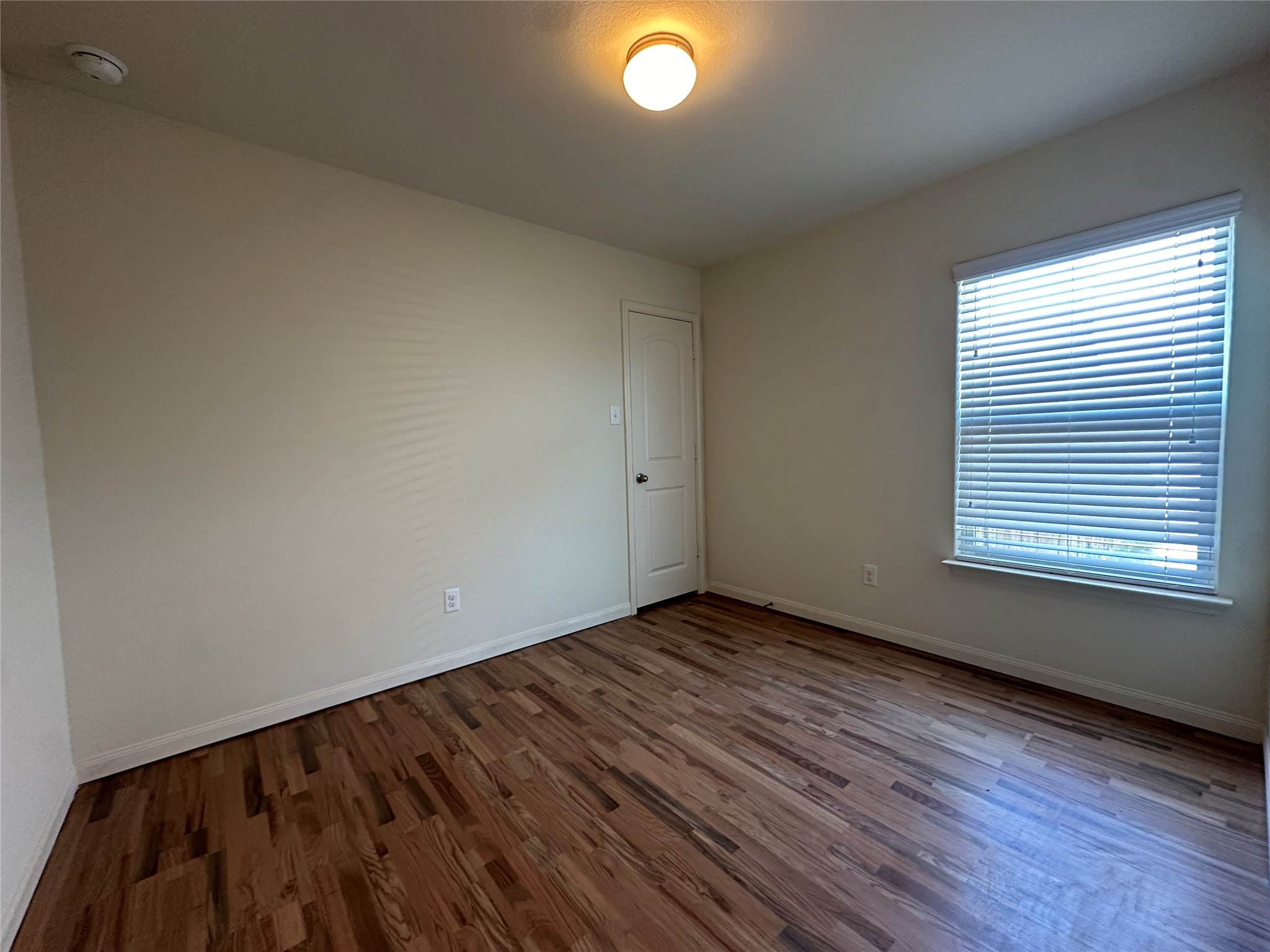 104 Millers Loop Jarrell, TX 76537 - Photo 10 of 11 This room features wood flooring, neutral colored walls, a window with blinds, and a ceiling-mounted light fixture