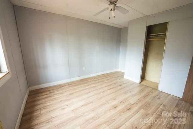 an empty room with wooden floor fan and windows