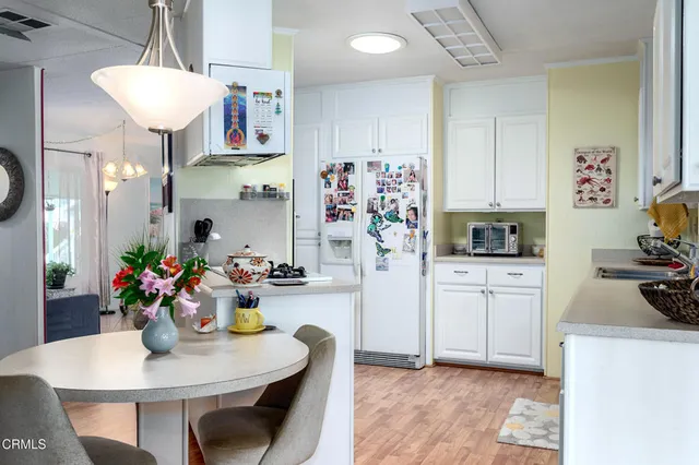 a kitchen with stainless steel appliances kitchen island granite countertop a dining table cabinets and a refrigerator