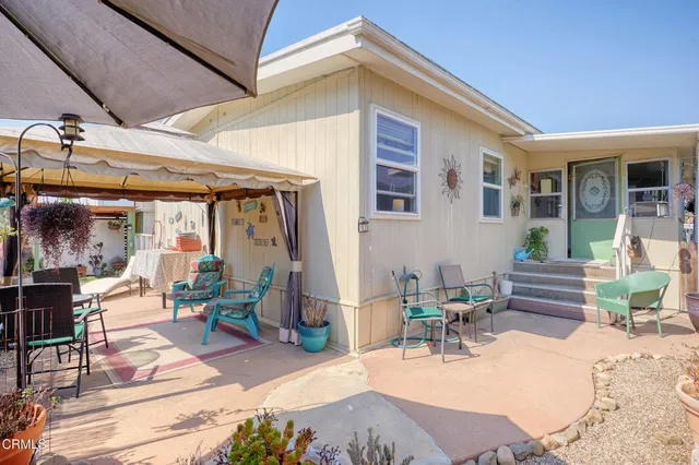 a view of a patio with table and chairs potted plants and floor to ceiling window