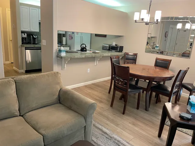 a living room with stainless steel appliances furniture and kitchen view