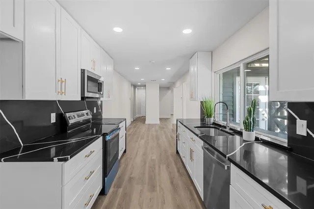 a kitchen with granite countertop a stove and white cabinets