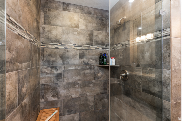 1132 Sunset Dunes Way Draper, UT 84020 - Photo 19 of 35 Walk-in shower featuring large format tile, a decorative mosaic accent band, and a glass enclosure