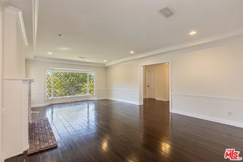 an empty room with wooden floor fireplace and windows