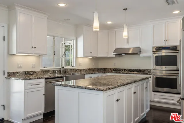 a kitchen with a refrigerator and white cabinets
