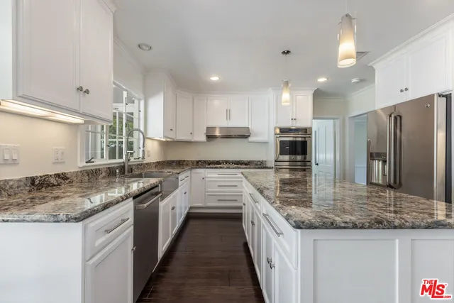 a kitchen with stainless steel appliances granite countertop a refrigerator and a stove top oven