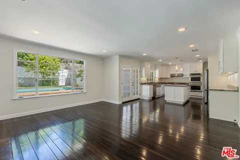 an empty room with wooden floor fireplace and windows