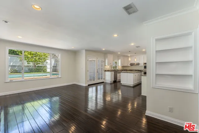 a view of an empty room with wooden floor and a fireplace