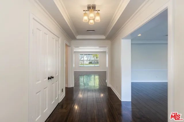 a view of a hallway with wooden floor and a chandelier