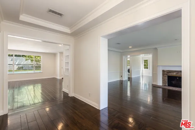 an empty room with wooden floor fireplace and staircase