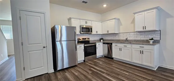 a kitchen with a refrigerator stove and white cabinets