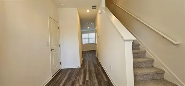 a view of a hallway with wooden floor and staircase