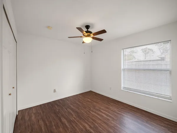 an empty room with a window and a ceiling fan