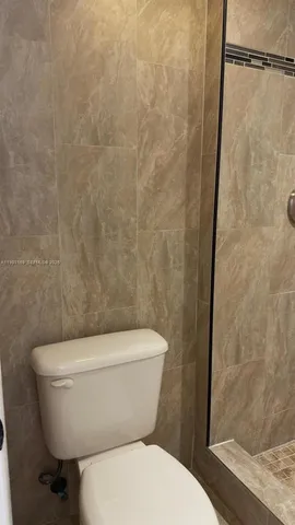 a white toilet sitting next to a shower