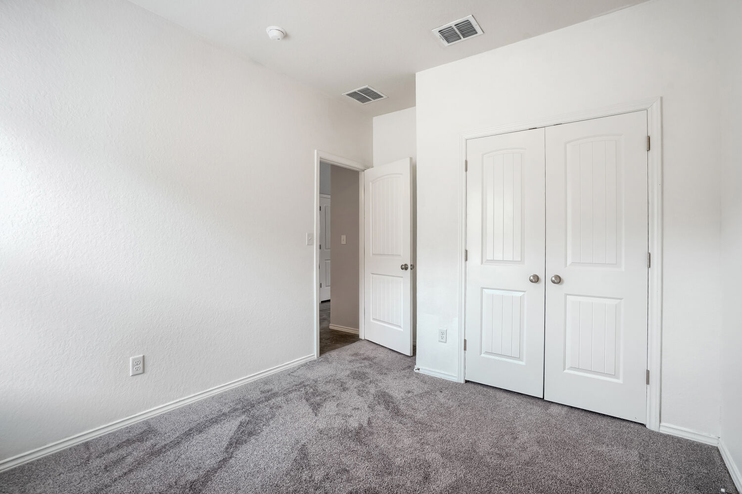 2420 Ranger Pass Seguin, TX 78155 - Photo 22 of 28 Bedroom featuring textured white walls, gray patterned carpeting, white baseboards, and a double-door closet with paneling