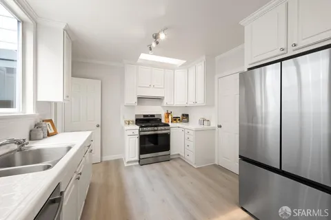 a kitchen with a sink white cabinets and stainless steel appliances