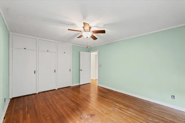a view of a room with wooden floor and a ceiling fan