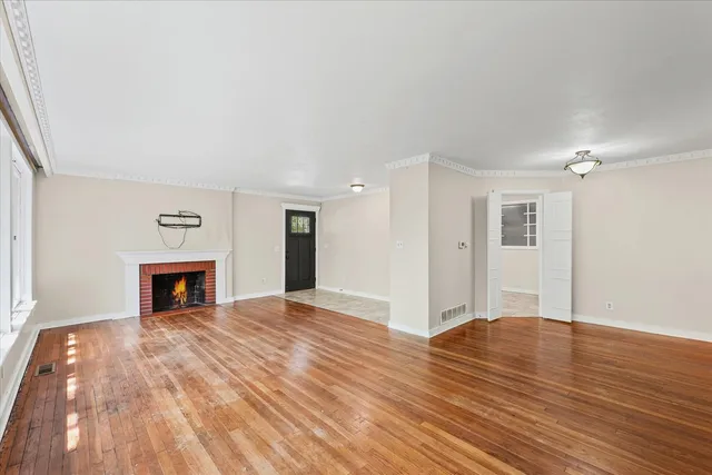 a view of an empty room with wooden floor fireplace and a window