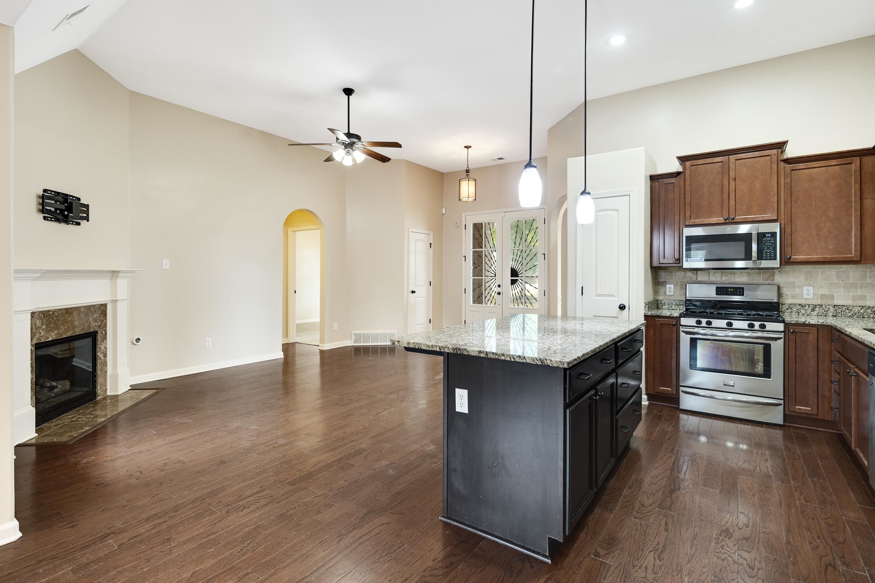 379 Shelton Road Collierville, TN 38017 - Photo 10 of 32 a large kitchen with stainless steel appliances granite countertop a stove a sink dishwasher a refrigerator and a fireplace with wooden floor