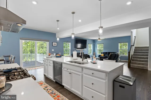 a kitchen with stainless steel appliances kitchen island granite countertop a dining table chairs refrigerator and microwave