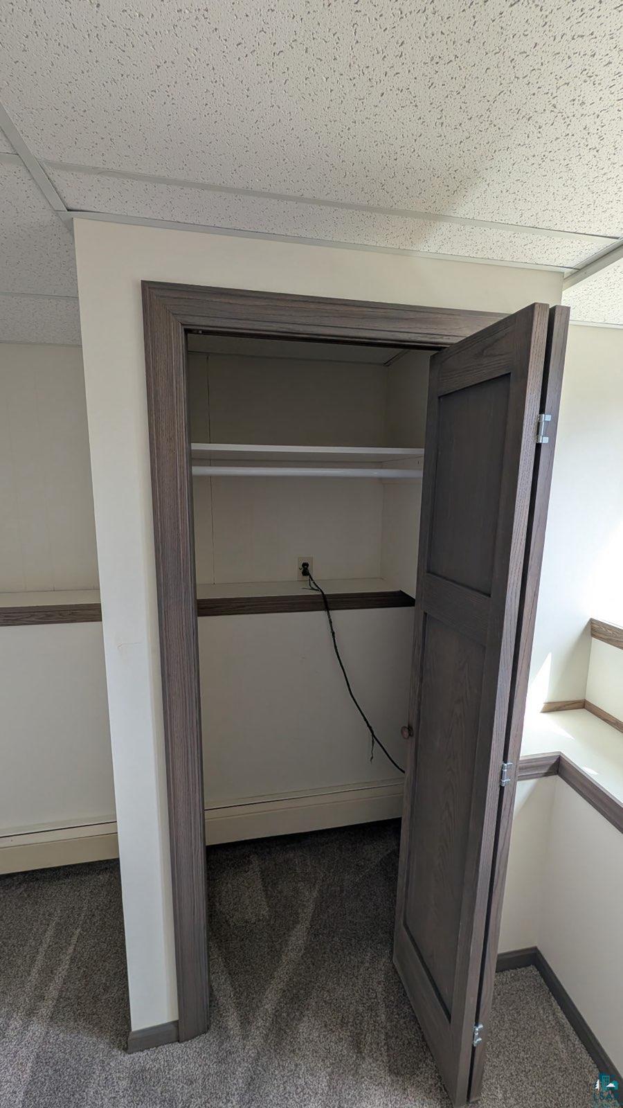 84 Erickson Road Esko, MN 55733 - Photo 16 of 16 Closet with bi-fold door, shelf, and hanging rod, featuring wood-finish trim, light grey carpeting, and a drop ceiling