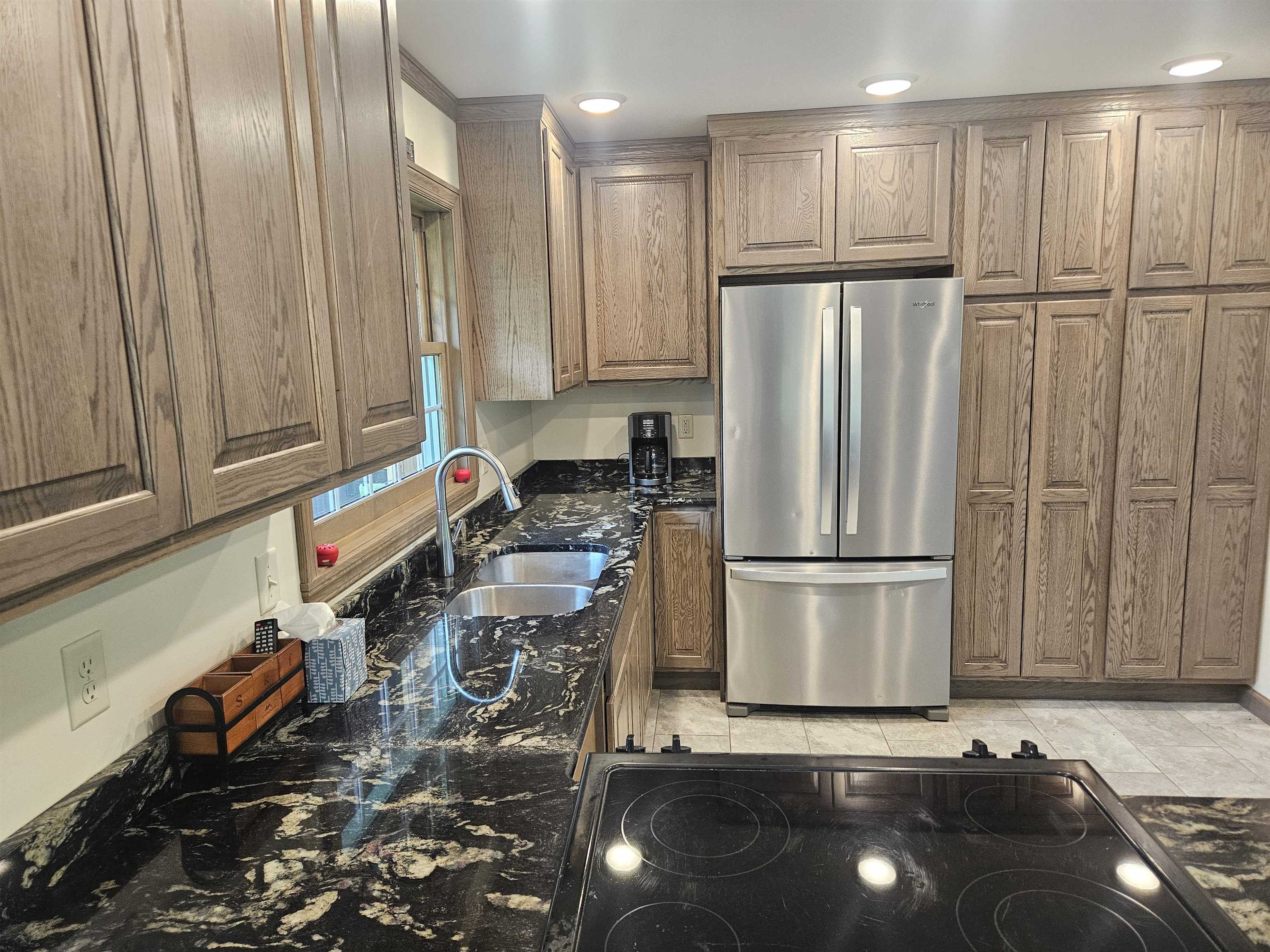 84 Erickson Road Esko, MN 55733 - Photo 6 of 16 Kitchen with freestanding refrigerator, dark stone countertops, black electric cooktop, and brown cabinetry