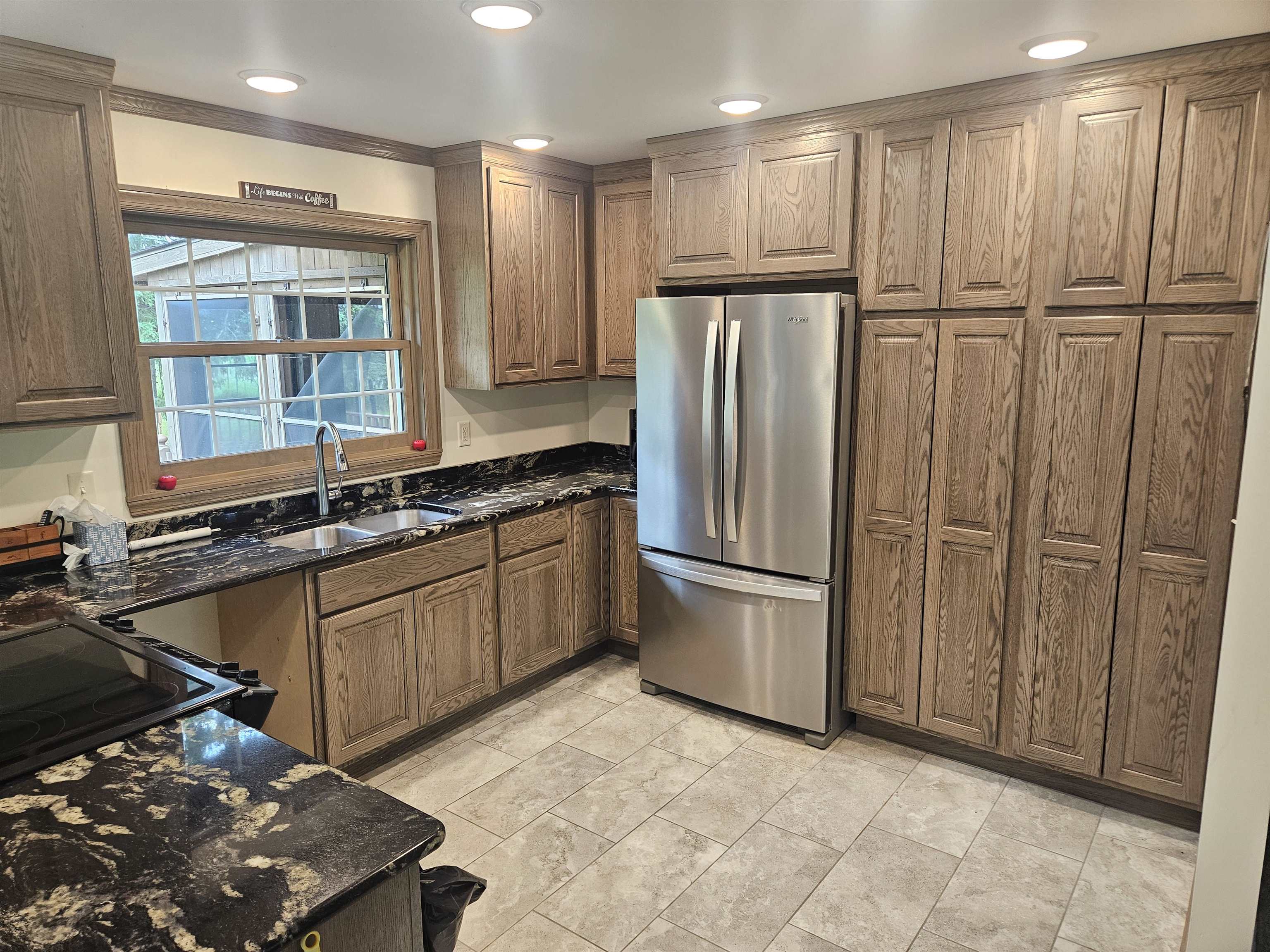 84 Erickson Road Esko, MN 55733 - Photo 9 of 16 Kitchen with dark stone countertops, freestanding refrigerator, brown cabinetry, crown molding, and recessed lighting