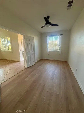 a view of empty room with wooden floor and fan