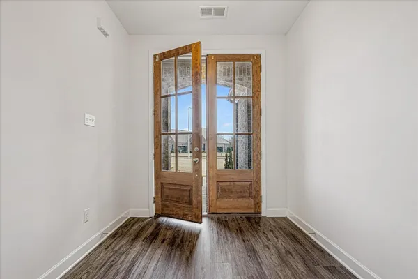 a view of a hallway with wooden floor and a kitchen