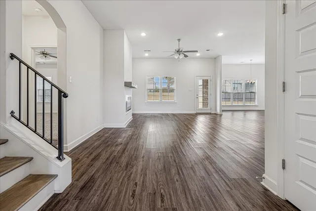 a view of a hallway with wooden floor and a kitchen