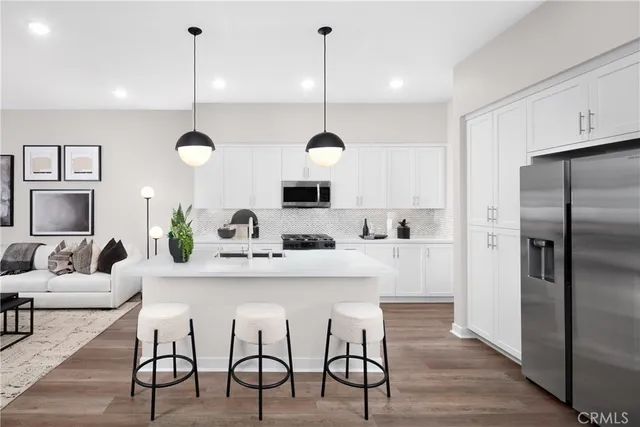 a kitchen with kitchen island a dining table chairs stainless steel appliances and cabinets