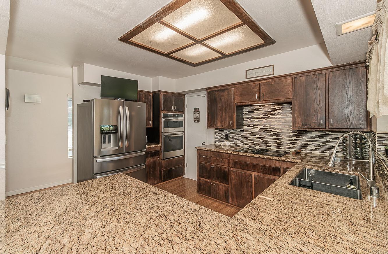 41371 Butte Way Madera, CA 93636 - Photo 18 of 84 a kitchen with stainless steel appliances kitchen island granite countertop a refrigerator stove and sink
