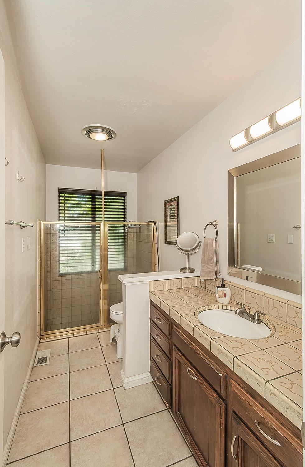 41371 Butte Way Madera, CA 93636 - Photo 23 of 84 a spacious bathroom with a granite countertop sink a toilet a mirror and shower