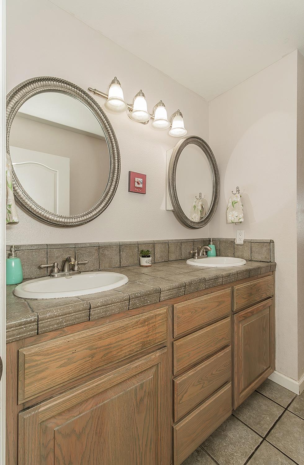 41371 Butte Way Madera, CA 93636 - Photo 35 of 84 a bathroom with a granite countertop double vanity sink and a mirror